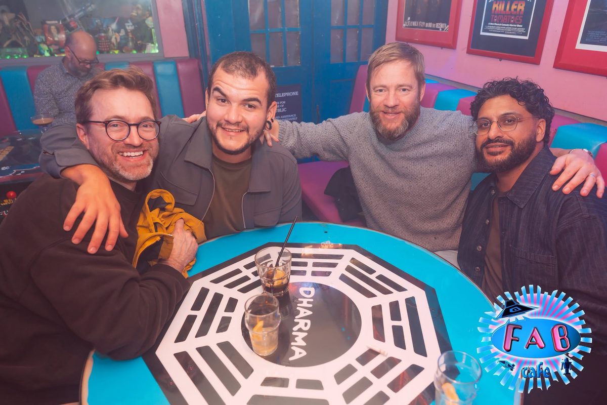 Four friends round a table painted like the Dharma hatch from Lost
